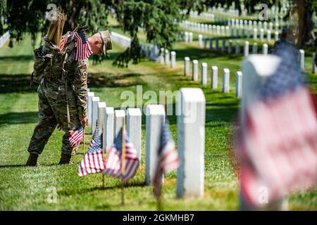 Ein Flieger hilft dabei, über 265,000 US-Flaggen an jeder Grabstätte, an jeder Kolumbariumhöfensäule und an jeder Nischenwandsäule als Teil von Flags-in auf dem Arlington National Cemetery, Arlington, Virginia, 27. Mai 2021 zu platzieren. Seit mehr als 50 Jahren ehren Soldaten der Alten Garde die gefallenen Militärhelden unseres Landes, indem sie US-Flaggen auf die Gräber von Dienstmitgliedern legen, die auf dem Nationalfriedhof von Arlington sowie auf dem National Cemetery der US-Soldaten und des Airmen's Home National Cemetery kurz vor dem Memorial Day-Wochenende begraben sind. Zum ersten Mal seit 20 Jahren, Mitglieder des U.S. Marine Corps, der U.S. Navy, der Stockfoto