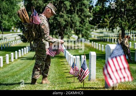 Ein Flieger hilft dabei, über 265,000 US-Flaggen an jeder Grabstätte, an jeder Kolumbariumhöfensäule und an jeder Nischenwandsäule als Teil von Flags-in auf dem Arlington National Cemetery, Arlington, Virginia, 27. Mai 2021 zu platzieren. Seit mehr als 50 Jahren ehren Soldaten der Alten Garde die gefallenen Militärhelden unseres Landes, indem sie US-Flaggen auf die Gräber von Dienstmitgliedern legen, die auf dem Nationalfriedhof von Arlington sowie auf dem National Cemetery der US-Soldaten und des Airmen's Home National Cemetery kurz vor dem Memorial Day-Wochenende begraben sind. Zum ersten Mal seit 20 Jahren, Mitglieder des U.S. Marine Corps, der U.S. Navy, der Stockfoto