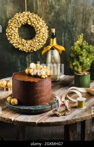 Schokoladen-weihnachtskuchen mit Champagner im Golddekor im rustikalen Stil Stockfoto