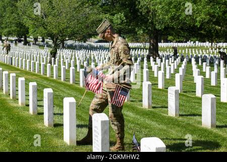 Der Fluggast Michael Hester der 1. Klasse, zusammen mit der Ehrenwache der US-Luftwaffe, platziert während des „Flags-in“, Mai 27, Flaggen auf Grabsteinen auf dem Arlington National Cemetery, Arlington, VA. 2021. Jedes Jahr vor dem Memorial Day werden auf jedem Grabstein auf dem Friedhof mehr als 260,000 Flaggen zu Ehren der gefallenen Helden des Landes aufgestellt. Stockfoto