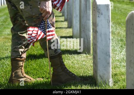 US Air Force Airman 1st Class Michael Hester, Ehrengarde der US Air Force, platziert während des „Flags-in“, 27. Mai, eine amerikanische Flagge auf dem Arlington National Cemetery, Arlington, VA. 2021. Jedes Jahr vor dem Memorial Day werden auf jedem Grabstein auf dem Friedhof mehr als 280,000 Flaggen zu Ehren der gefallenen Helden der Nationen aufgestellt. Stockfoto