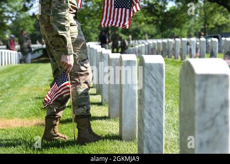 US Air Force Airman 1st Class Michael Hester, Ehrengarde der US Air Force, platziert während des „Flags-in“, 27. Mai, eine amerikanische Flagge auf dem Arlington National Cemetery, Arlington, VA. 2021. Jedes Jahr vor dem Memorial Day werden auf jedem Grabstein auf dem Friedhof mehr als 280,000 Flaggen zu Ehren der gefallenen Helden der Nationen aufgestellt. Stockfoto