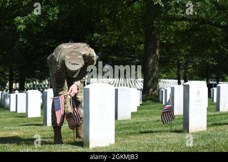 US Air Force Airman 1st Class Michael Hester, Ehrengarde der US Air Force, platziert während des „Flags-in“, 27. Mai, eine amerikanische Flagge auf dem Arlington National Cemetery, Arlington, VA. 2021. Jedes Jahr vor dem Memorial Day werden auf jedem Grabstein auf dem Friedhof mehr als 280,000 Flaggen zu Ehren der gefallenen Helden der Nationen aufgestellt. Stockfoto