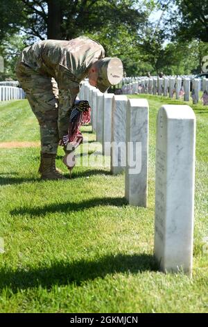 US Air Force Airman 1st Class Michael Hester, Ehrengarde der US Air Force, platziert während des „Flags-in“, 27. Mai, eine amerikanische Flagge auf dem Arlington National Cemetery, Arlington, VA. 2021. Jedes Jahr vor dem Memorial Day werden auf jedem Grabstein auf dem Friedhof mehr als 280,000 Flaggen zu Ehren der gefallenen Helden der Nationen aufgestellt. Stockfoto