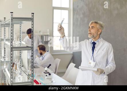 Seriöser, leitender Wissenschaftler, der in einem modernen Wissenschaftslabor mit chemischen Proben arbeitet. Stockfoto