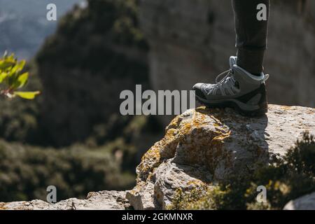 Wanderschuhe, die an sonnigen Tagen auf einem kleinen Felsen mit verschwommenem Landschaftshintergrund treten. Speicherplatz kopieren. Stockfoto