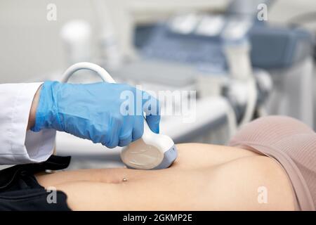 Frau, die vom Arzt Ultraschall einer Schilddrüse bekommt. Stockfoto