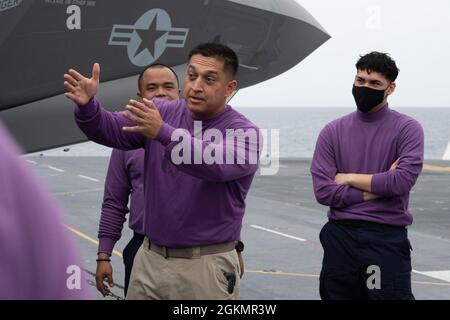 PACIFIC OCEAN (29. Mai 2021) Julio Bejarano, Chief Aviation Boatswain’s Mate (Fuel) von Hagerman, N.M., der dem nach vorne eingesetzten amphibischen Sturmschiff USS America (LHA 6) zugewiesen wurde, unterrichtet Juniorsegler über den Flugdecksbetrieb mit F-35B Lightning II Kampfflugzeugen auf dem Flugdeck des Schiffes. America, das führende Schiff der America Amphibious Ready Group, ist im Einsatzgebiet der 7. US-Flotte tätig, um die Interoperabilität mit Verbündeten und Partnern zu verbessern und als Ready Response Force zur Verteidigung von Frieden und Stabilität in der Region Indo-Pazifik zu dienen. Stockfoto