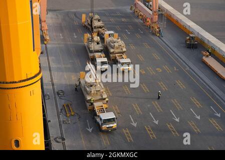 Hafen von Shuaiba, Kuwait, Hafenarbeiter werden während des 2. Juni 2021 während der Operationen, die von „Sentinel“-Soldaten des 1185. Einsatz- und Distributionsunterstützungs-Bataillons der Army Reserve, Lancaster, Pennsylvania, überwacht wurden, mit einem Kran und einem Abrams-Panzer hochgehoben. Diese Panzer gehören zum Kampfteam der 2. Panzerbrigade, dem Arsenal der 1. Panzerdivision, und werden nach dem Einsatz der Brigade im Nahen Osten nach Fort Bliss, Texas, zurückgeschickt. Stockfoto