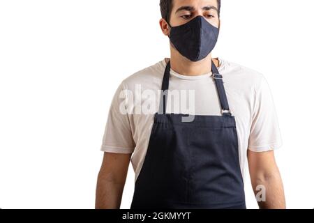 Der Barista trägt eine schwarze Schürze und eine Gesichtsschutzmaske, die vor weißem Hintergrund isoliert ist. Kaffee- und Lebensmittelgeschäft neues Konzept der normalen Coronavirus-Tage Stockfoto
