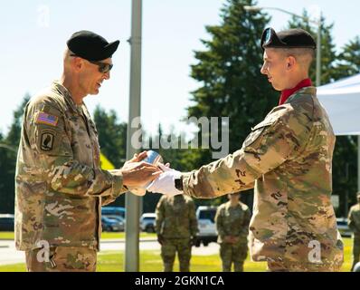 First LT. Andrew Schwab, Salute Battery Officer, verantwortlich für B Battery, 1. Bataillon, 137. Field Artillery Regiment, 1-2 Stryker Brigade Combat Team, 7. Infanterie Division, präsentiert Amerikas ersten Corps ausscheidenden Kommandanten, LT. General Randy A. George, Mit einem Gehäuse aus einer Kanonenhülle als symbolische Geste während einer Übergabe der Kommandozeremonie auf der Joint Base Lewis-McChord, Washington, 2. Juni 2021. Stockfoto