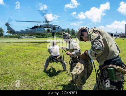 210602-N-JO829-1411 Hafen APRA, Guam (2. Juni 2021) Segler, die der Task Group 75.1/Explosive Ordnance Disposal Mobile Unit (EODMU) 5 zugeordnet sind, halten die Spannung an einer Schnur, die an einem Sea Hawk-Hubschrauber des Hubschraubers MH-60S Sea Hawk vom Helicopter Sea Combat Squadron (HSC) 21 befestigt ist, während einer Abstoßtrainingsentwicklung auf dem 5-Gelände von CTG 75.1/EODMU aufrecht. Als Teil von Destroyer Squadron Seven wird HSC-21 dem Littoral Combat Ship USS Tulsa (LCS 16) mit Independence-Variant zugewiesen, das im Einsatzgebiet der 7. US-Flotte eingesetzt wird, um die Interoperabilität mit Partnern zu verbessern und als einsatzbereite Hilfstruppe zu dienen Stockfoto
