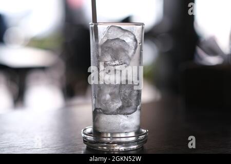 Ein Glas, halb voll mit Eiswürfeln, an einem heißen Tag Stockfoto