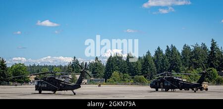 UH-60 Blackhawk-Hubschrauber der Firma B, 2-158 Assault Helicopter Bataillon, 16. Kampfluftfahrtbrigade, werden während Routineoperationen auf der Joint Base Lewis McChord, Washington, am 3. Juni 2021 durchgeführt. Im Hintergrund ist der Mount Rainier zu sehen, ein schlafender Vulkan und Teil des pazifischen Feuerrings. Stockfoto