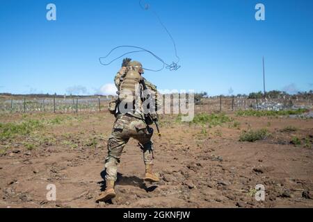 Ein Kampfingenieur, der dem 29. Brigadeingenieur-Bataillon, dem Kampfteam der 3. Infanteriebrigade, der 25. Infanteriedivision, zugewiesen wurde, wirft am 5. Juni 2021 bei einer Koordinationsübung zur Brandunterstützung im Trainingsgebiet Pohakuloa, Hawaii, einen Greifhaken. Diese Übung ermöglichte es Führungskräften auf Unternehmensebene und darunter, ein tieferes Verständnis dafür zu erlangen, wie verschiedene Vermögenswerte während eines großen, bewussten Betriebs ordnungsgemäß implementiert werden können. Stockfoto