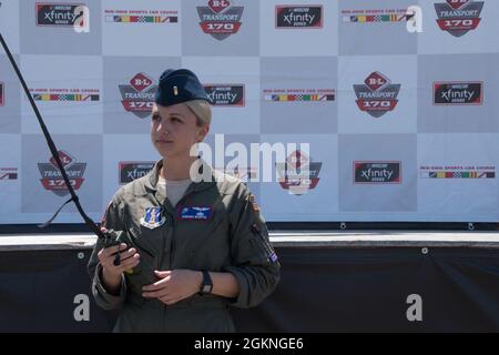 First Lieutenant Samanda McGiffin, ein Mitglied der 164. Airlift Squadron am 179. Airlift Wing, posiert mit einem Radio vor der Hauptbühne auf dem Mid-Ohio Sports Car Course am 5. Juni 2021. McGriffin diente während des Überfluges als Bodenkontrolle und kommunizierte mit der Crew im Flugzeug, um den Überflug mit der Leistung der Nationalhymne zu zeitlich zu planen. Stockfoto