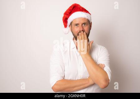 Überraschender junger Mann mit weihnachtsmannhut auf isoliertem weißem Hintergrund. Stockfoto