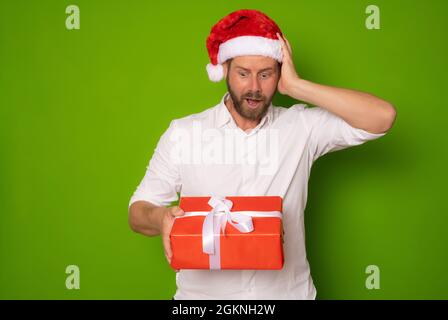 Junger, hübscher Mann mit Weihnachtsgeschenk. Isoliert auf grünem Hintergrund Stockfoto