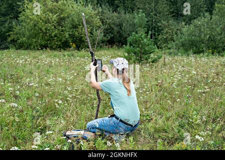 Junge Frau Wissenschaftler Biologe Zoologe stellt Kamera Falle für die Beobachtung von wilden Tieren im Sommer Taiga Wald zu sammeln wissenschaftliche Daten Umwelt Stockfoto