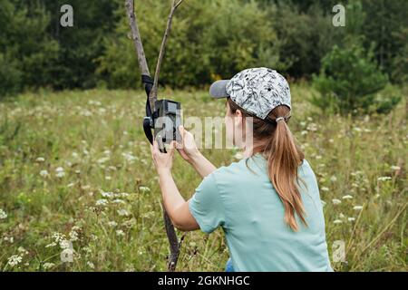 Junge Frau Wissenschaftler Biologe Zoologe stellt Kamera Falle für die Beobachtung von wilden Tieren im Sommer Taiga Wald zu sammeln wissenschaftliche Daten Umwelt Stockfoto