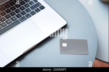 Laptop, elektronische Chipkarte und Smartphone auf blauem Rundtisch. Online-Zahlung oder Kundenidentifikation. Moderne Technologie, drahtlose Geräte und Transf Stockfoto