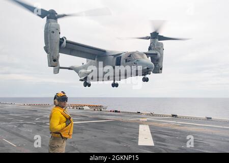 PHILLIPINE SEA ( 7. Juni 2021) Eduardo Aceves, der dem nach vorne eingesetzten amphibischen Angriffsschiff USS America (LHA 6) zugeschobene Mate (Handling) des Chefs Aviation Boatswain, überwacht das Flugdeck des Schiffes, während ein MV-22B Osprey an der 31. Marine Expeditionary Unit (MEU) befestigt ist, Marine Medium Tiltrotor Squadron (VMM) 265 (verstärkt), landet während des Fluges. America, das führende Schiff der America Amphibious Ready Group, ist zusammen mit der 31. MEU im Einsatzgebiet der 7. US-Flotte tätig, um die Interoperabilität mit Verbündeten und Partnern zu verbessern und als ready Respo zu dienen Stockfoto