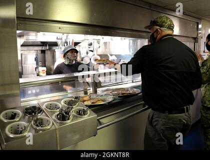 210608-N-OH262-0704 NORFOLK, VA. (8. Juni 2021) - ein ziviler Seefahrer, der dem ozeanographischen Vermessungsschiff des Militärkommandos USNS Bruce C. Heezen (T-AGS 64) zugewiesen wurde, bereitet am 8. Juni in der Schiffskollege das Mittagessen zu, während das Schiff auf See war. Die Seeleute, die USNS Bruce C. Heezen besetzen, sind bei der beauftragten Betreibergesellschaft Ocean Ships, Inc. Beschäftigt Stockfoto