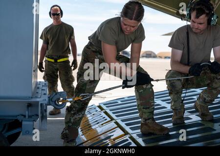 Airman 1st Class Rebecca Reimer, Mitte, 9th Airlift Squadron Student Loadmaster, und Staff Sgt. John Dittess, rechts, 9. ALS Ladermeister, befestigen Sie eine Winde an der Bodenausrüstung des Flugzeugs, bevor Sie sie während eines Major Command Service Tail Trainer auf eine Dover Air Force Base C-5M Super Galaxy auf der Holloman AFB, 8. Juni 2021, laden. Loadmasters vom 9. ALS koordinierte Fracht mit den Luftfahrtscharen vom 49. Flügel des Air Education and Training Command und der 635. Materialwartungsgruppe des Air Force Materials Command, um die 10-tägige MSTT abzuschließen. Im Laufe des Trainings beladen und entladen Airmen 320,085 Pfund Stockfoto