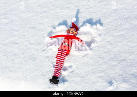 Eine freche Weihnachtselfe, die im frischen Winterschnee Schnee macht. Elf im Regal, frech, weihnachten, schelmische Elf-Konzept Stockfoto