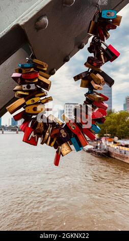 FRANKFURT, DEUTSCHLAND - 23. Jul 2021: Die farbenfrohen Love-Vorhängeschlösser, die an der eisernen Fußgängerbrücke in Frankfurt hängen Stockfoto