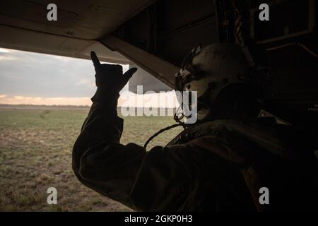 U.S. Marine Corps CPL. Jason Willoughby, ein Crewchef mit Marine Medium Tiltrotor Squadron 363 (verstärkt), Marine Rotational Force – Darwin, gibt vor dem Start im Mount Bundey Training Area, NT, Australien, am 9. Juni 2021 ein klares Signal von einem MV-22B Osprey ab. MV-22B Osprey Piloten übten Touch-and-Go und andere taktische Manöver während MBTA. Die Ausbildung unterstützt die Fähigkeiten der Marines als qualifizierte Expeditionskämpfer, die in der Lage sind, auf eine potenzielle Krise oder eine mögliche Notlage zu reagieren. Stockfoto