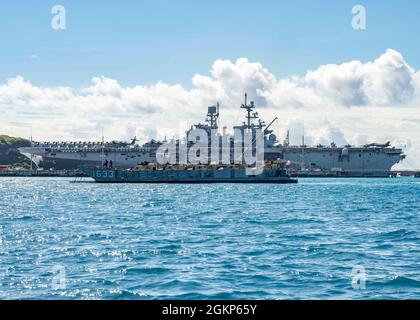 WHITE BEACH, Japan (Jun. 10, 2021) Ein Landungsschiff auf dem Weg zur Anlegestelle der Whidbey Island-Klasse USS Germantown (LSD 42) passiert das amphibische Angriffsschiff USS America (LHA 6) der amerikanischen Klasse bei Commander, Fleet Activities Okinawa White Beach Naval Facility, Okinawa, Japan, 10. Juni 2021. Stockfoto