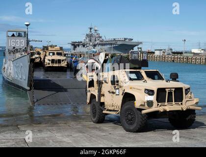 WHITE BEACH, Japan (Jun. 10, 2021) A III Marine Expeditionary Force gemeinsame leichte taktische Fahrzeuge begibt sich auf ein Landungsschiff Dienstprogramm in Commander, Fleet Activities Okinawa White Beach Naval Facility, Okinawa, Japan 10. Juni 2021. Das amphibische Angriffsschiff USS America (LHA 6) der amerikanischen Klasse liegt an der Pier-Seite im Hintergrund. Stockfoto