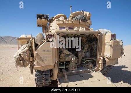 Soldaten des 1. Bataillons, des 155. Infanterie-Regiments, der Nationalgarde der Mississippi-Armee, bereiten sich darauf vor, während des Angriffstrainings im National Training Center, Fort Irwin, Kalifornien, am 12. Juni 2021 ein Kampffahrzeug der M2A2 Bradley abzusteigen. Die Bradley wurde entwickelt, um Infanterie oder Kundschafter mit Panzerschutz zu transportieren, während sie das Feuer schützt, um gegnerische Kräfte zu unterdrücken. Stockfoto