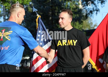 Der Oberbefehlshaber der US-Armee 2 Cody Mallchok, der dem 2. Bataillon, 1. Luftfahrtregiment, zugewiesen wurde, erhält eine Challenge-Münze von Col. Bryan Chivers, Kommandant der 1. Kampfluftfahrtbrigade, weil er der erste Teilnehmer bei einem 5-km-Rennen in den Storck Barracks, Deutschland, am 14. Juni 2021 war. Das Rennen wurde zur Feier des Geburtstages der US-Armee abgehalten. Stockfoto