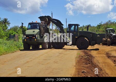 TINIAN, Commonwealth of Nördliche Marianen (14. Juni 2021) Seekühe, die dem Naval Mobile Construction Bataillon (NMCB) 4 zugewiesen wurden, entfernen überschüssiges Material aus dem Projekt Marpo Heights Road. NMCB-4 wird im gesamten Indo-Pazifik-Raum und in den Vereinigten Staaten eingesetzt, um größere Kampfeinsätze, Theatersicherheit, humanitäre Hilfe und Katastrophenhilfe zu unterstützen. Seabees bietet allgemeine technische und zivile Unterstützung für die Marine, das Marine Corps und gemeinsame Einsatzkräfte weltweit. Stockfoto