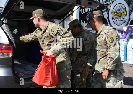 Soldaten der Nationalgarde der Arizona Army lieferten Lebensmittel und andere Gegenstände an Bewohner der Gegend an einer Einfahrungs- und begehbaren Lebensmittelbank in Phoenix, 15. Juni 2021. Die Arizona National Guard hat mehr als 800 Arizona Bürger-Soldaten und Luftmänner aktiviert, um die Bedürfnisse der Gemeinschaft während dieses Ausnahmezustands zu unterstützen. Stockfoto