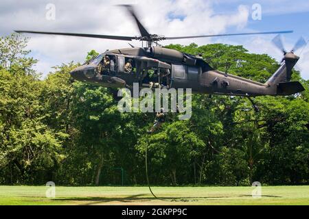 Ein Mitglied der Costa-ricanischen Polizei forciert schnelle Seile aus einem Hubschrauber der US-Armee UH-60 Blackhawk, der dem 1. Bataillon, 228. Aviation Regiment, Joint Task Force-Bravo, Soto Cano Air Base, Honduras, während des Fast-Rope Insertion and Extraction System (FRIES) Trainings in Liberia, Costa Rica, 15. Juni 2021, zugewiesen wurde. Das System wird in Situationen eingesetzt, in denen das Gelände ein Flugzeug von der Landung abhält und die Servicemitarbeiter schnell zum Ziel gelangen müssen. Stockfoto