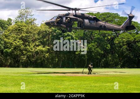 Ein Mitglied der Costa-ricanischen Polizei forciert schnelle Seile aus einem Hubschrauber der US-Armee UH-60 Blackhawk, der dem 1. Bataillon, 228. Aviation Regiment, Joint Task Force-Bravo, Soto Cano Air Base, Honduras, während des Fast-Rope Insertion and Extraction System (FRIES) Trainings in Liberia, Costa Rica, 15. Juni 2021, zugewiesen wurde. Das System wird in Situationen eingesetzt, in denen das Gelände ein Flugzeug von der Landung abhält und die Servicemitarbeiter schnell zum Ziel gelangen müssen. Stockfoto