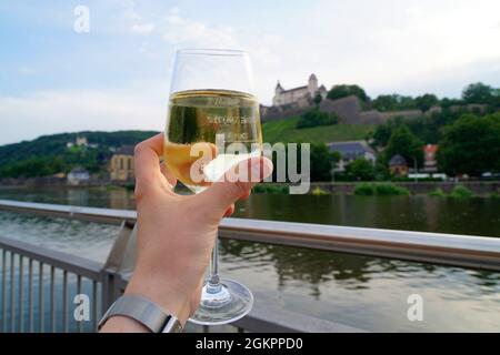 Ein Glas knackiger halbtrockener Weißwein mit Festung Marienberg und den Weinbergen im Hintergrund an einem schönen Frühlingstag in Würzburg Stockfoto