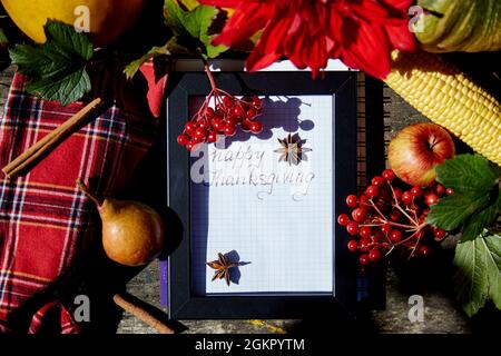 Handschriftliche Glückwünsche zum Thanksgiving Day-Gruß in einem Rahmen zwischen herbstlichem Gemüse: dahlien, Birne, Zimtstangen und Viburnum. Hohe Qualität Stockfoto