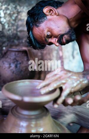 Konzentrierter indischer Töpfer Künstler, der Tontopf oder auf traditionellem Karrenrad macht - Koncep von handwerklicher Arbeit, Armut, traditioneller Kultur und lokalem Stockfoto