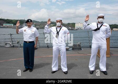 YOKOSUKA, Japan (17. Juni 2021) – von links nach rechts, US Army SPC. Rigoberto Montoya Arcega, gebürtiger Mexikaner, der im Camp Zama der medizinischen Abteilung Japan angeschlossen ist, Feuerwehrmann Carl Jefferson Robles Dela Cruz, gebürtiger Philippiner, der an den Aegis-Lenkungsjäger USS Milius der Arleigh Burke-Klasse (DDG 69) angeschlossen ist, Und Gasturbinen-Systemtechniker Mechanik 3. Klasse Patrick Luis Mendoza Abad, ein gebürtiger Philippiner, der an die USS Chancellorsville (CG 62) angeschlossen ist, legt während einer Einbürgerungszeremonie an Bord von Milius, der bei Commander, Fleet Activit, stationiert ist, den Eid der Allegiance ab Stockfoto