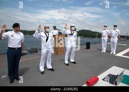 YOKOSUKA, Japan (17. Juni 2021) – von links nach rechts, US Army SPC. Rigoberto Montoya Arcega, gebürtiger Mexikaner, der im Camp Zama der medizinischen Abteilung Japan angeschlossen ist, Feuerwehrmann Carl Jefferson Robles Dela Cruz, gebürtiger Philippiner, der an den Aegis-Lenkungsjäger USS Milius der Arleigh Burke-Klasse (DDG 69) angeschlossen ist, Und Gasturbinen-Systemtechniker Mechanik 3. Klasse Patrick Luis Mendoza Abad, ein gebürtiger Philippiner, der an die USS Chancellorsville (CG 62) angeschlossen ist, legt während einer Einbürgerungszeremonie an Bord von Milius, der bei Commander, Fleet Activit, stationiert ist, den Eid der Allegiance ab Stockfoto