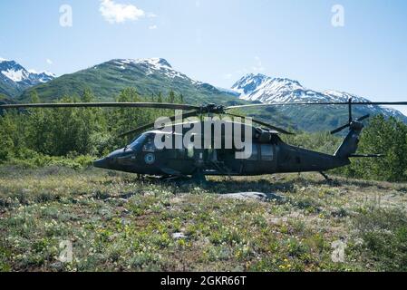 Ein Hubschrauber der Alaska Army National Guard UH-60 Black Hawk sitzt am Fuß der Chugach Mountain Range, Alaska, nachdem er an einem abgelegenen Wetterbeobachtungsposten gelandet ist, um Lieferungen zur Unterstützung der Operation Colony Glacier am 17. Juni 2021 zu liefern. Die Operation Colony Glacier ist ein Versuch, die Überreste von Dienstmitgliedern und Wracks eines C-124-Flugzeuges, das im November 1952 mit 52 Militärmitgliedern an Bord gelandet war, zu retten. Das Wrack wurde 2012 entdeckt und jeden Sommer findet eine Erholung statt. Dies wird das neunte Jahr der Wiederauffüllungsbemühungen sein. Stockfoto