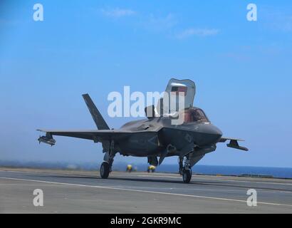 Eine US-Marine mit Marine Fighter Attack Squadron (VMFA) 211, Carrier Strike Group (CSG) 21, bereitet sich auf den Start eines F-35B Lightning II vom Flugdeck der HMS Queen Elizabeth im 6. Einsatzgebiet der Flotte am 18. Juni 2021 vor. Neben dem britischen 617-Squadron führt VMFA-211 Kampfhandlungen zur Unterstützung der Operation Inhärent Resolve (OIR) durch, der ersten Kampfoperationen, die von der HMS Queen Elizabeth gestartet wurden. OIR ist die Operation zur Beseitigung der Terrorgruppe des IS und der Bedrohung, die sie für den Irak, Syrien und die allgemeine internationale Gemeinschaft darstellen. Stockfoto