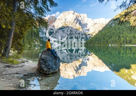 Wanderer genießen den Sonnenaufgang auf Felsen am Ufer des Pragser Wildsees bei Sonnenaufgang, Dolomiten, Südtirol, Italien, Europa Stockfoto