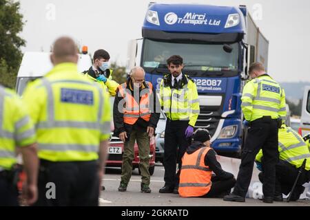 Enfield, Großbritannien. September 2021. Metropolitan Police Officers verhaften einen beleidigenden britischen Klimaaktivisten, der im Rahmen einer Kampagne, die die britische Regierung dazu drängen sollte, erhebliche Gesetzesänderungen vorzunehmen, um die Emissionen zu senken, eine Zufahrtsstraße von der M25 an der Kreuzung 25 blockiert hatte. Die Aktivisten, die am 13. August an Premierminister Boris Johnson schrieben, Fordern, dass die Regierung unverzüglich verspricht, sowohl die vollständige Finanzierung und Isolierung des gesamten sozialen Wohnungsbaus in Großbritannien bis 2025 sicherzustellen als auch innerhalb von vier Monaten einen rechtlich verbindlichen nationalen Plan zur vollständigen Finanzierung und Sicherstellung des Fu zu erstellen Stockfoto