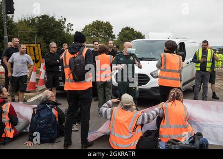 Enfield, Großbritannien. September 2021. Ein Krankenwagenfahrer fordert britische Klimaaktivisten auf, sich aus einer Zufahrtsstraße von der M25 an der Kreuzung 25 zu entfernen, die sie im Rahmen einer Kampagne blockierten, die die britische Regierung dazu drängen sollte, erhebliche Gesetzesänderungen vorzunehmen, um die Emissionen zu senken. Die Aktivisten, Die am 13. August an Premierminister Boris Johnson geschrieben haben, fordern, dass die Regierung unverzüglich verspricht, sowohl die vollständige Finanzierung als auch die Isolierung des gesamten sozialen Wohnungsbaus in Großbritannien bis 2025 sicherzustellen und innerhalb von vier Monaten einen rechtsverbindlichen nationalen Plan zur vollständigen Finanzierung und en zu erstellen Stockfoto