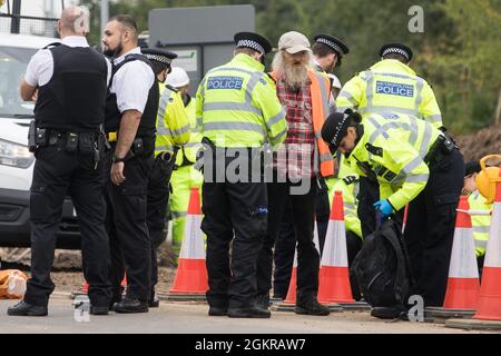 Enfield, Großbritannien. September 2021. Metropolitan Police Officers verhaften einen beleidigenden britischen Klimaaktivisten, der im Rahmen einer Kampagne, die die britische Regierung dazu drängen sollte, erhebliche Gesetzesänderungen vorzunehmen, um die Emissionen zu senken, eine Zufahrtsstraße von der M25 an der Kreuzung 25 blockiert hatte. Die Aktivisten, die am 13. August an Premierminister Boris Johnson schrieben, Fordern, dass die Regierung unverzüglich verspricht, sowohl die vollständige Finanzierung und Isolierung des gesamten sozialen Wohnungsbaus in Großbritannien bis 2025 sicherzustellen als auch innerhalb von vier Monaten einen rechtlich verbindlichen nationalen Plan zur vollständigen Finanzierung und Sicherstellung des Fu zu erstellen Stockfoto